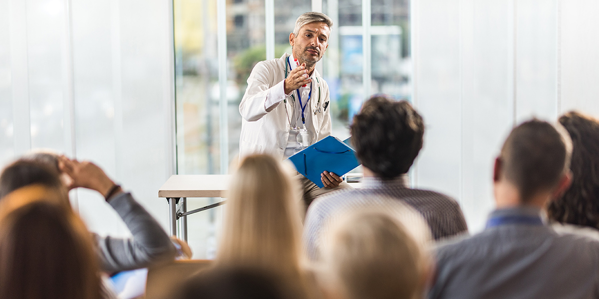 Doctor speaking in front of seated crowd