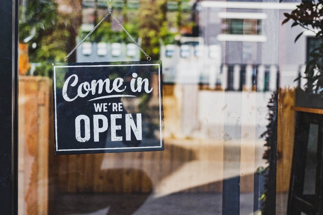 Come In, We're Open sign hanging on a glass door