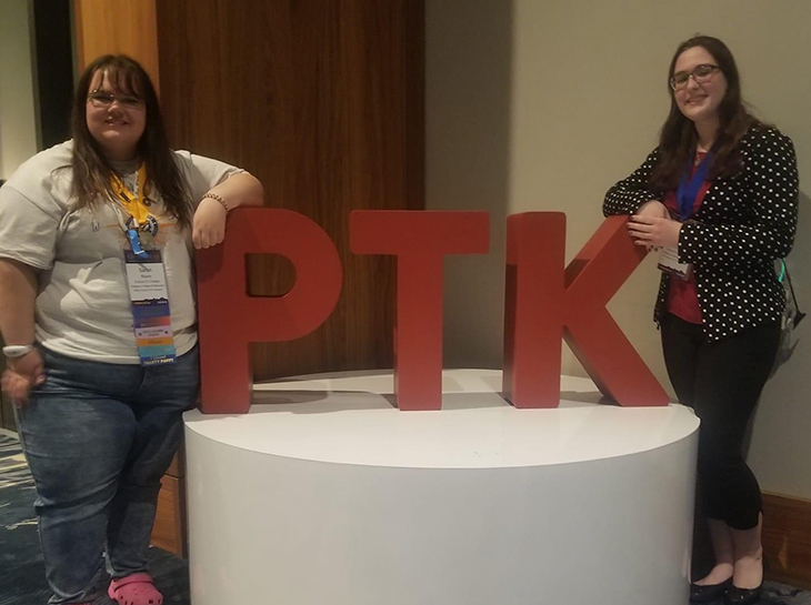 2 students standing with PTK sign