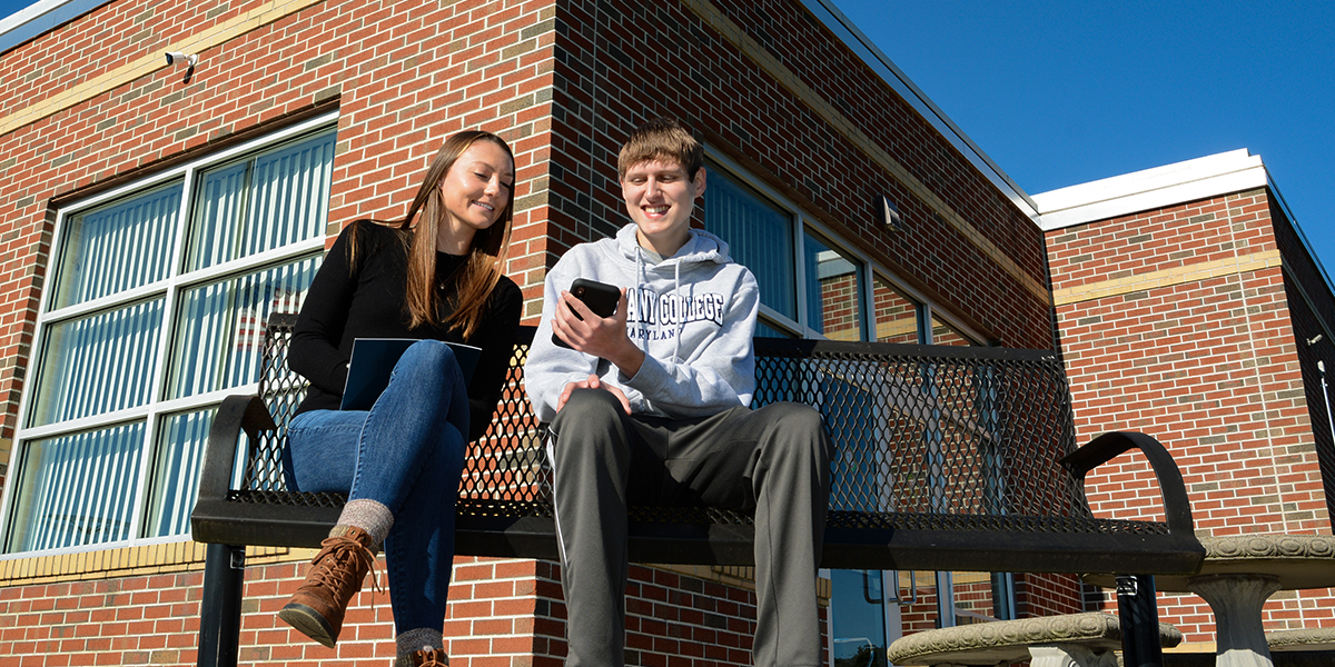 Students sitting on rock reading books