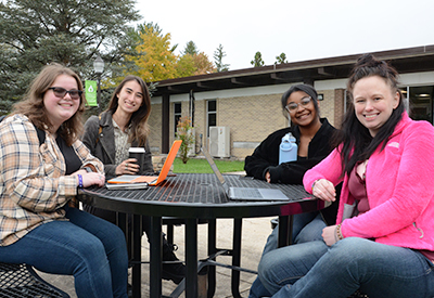 Four ACM students at table outdoors