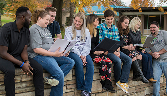 students sitting on outdoor wall